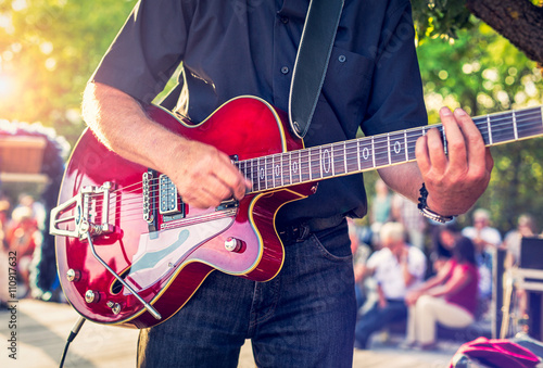 Obraz na płótnie Man with a red electric guitar in the park playing a summer concert w salonie