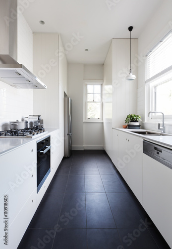 Billede på lærred Vertical of a long galley style monochrome kitchen