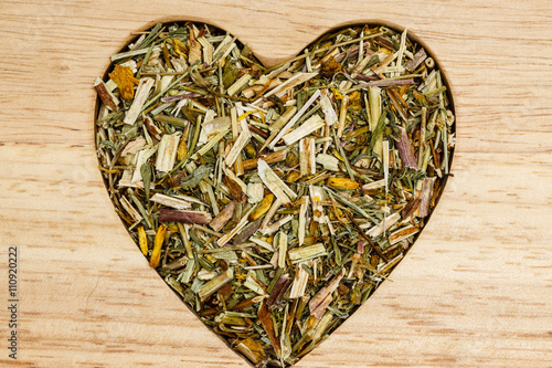 Dried herb leaves heart shaped on wooden surface