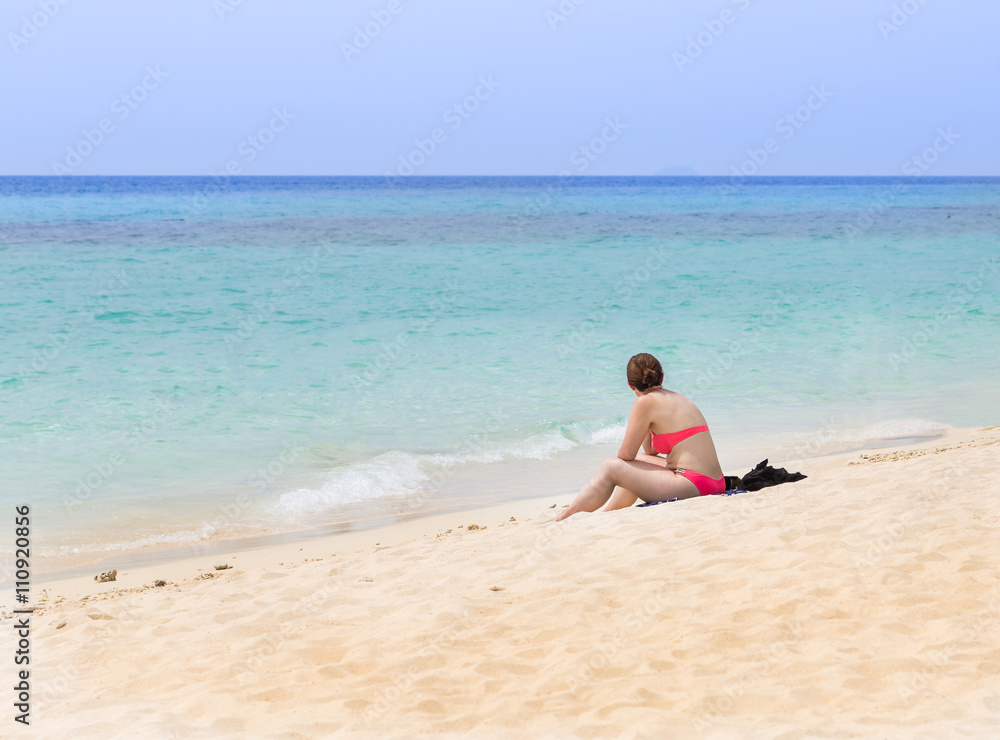 woman sitting on the beach looking in the sea.