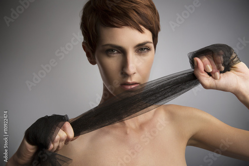 Studio portrait of woman pulling black silk scarf around hands