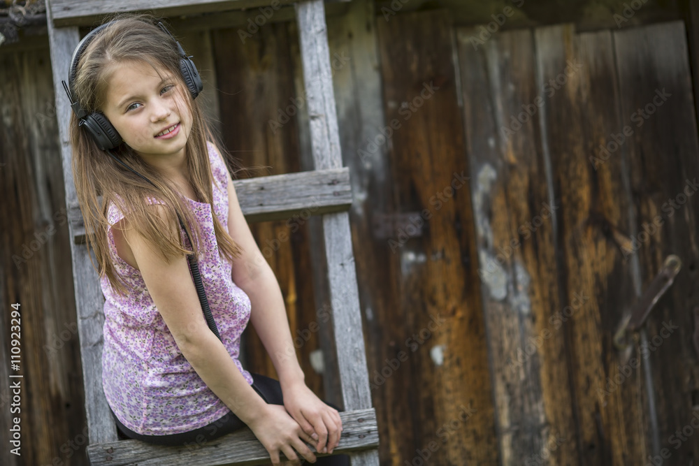 Fototapeta premium Cute little girl with headphones, portrait outdoors.