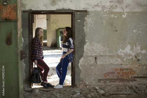 Two teen girls standing in the aisle in an abandoned building. © De Visu