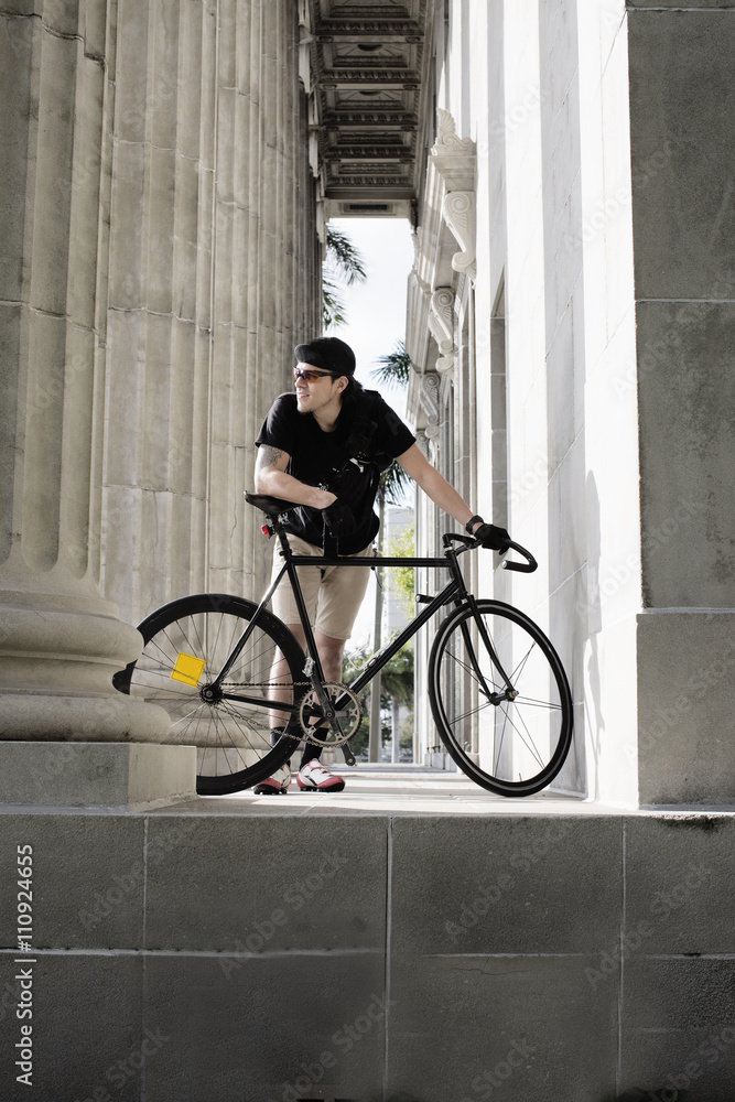 Bike messenger taking break beside column Bike messenger taking break beside column