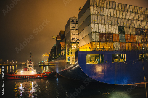 Tugboat manoeuvring container ship on river at night, Tacoma, Washington, USA photo