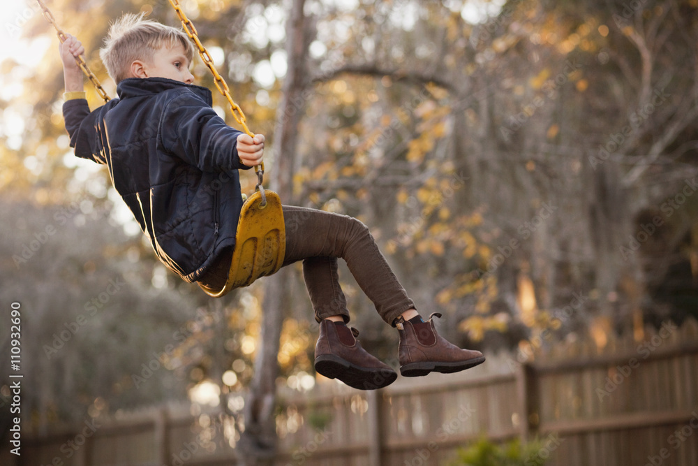 Young boy swinging high on garden swing Stock Photo | Adobe Stock