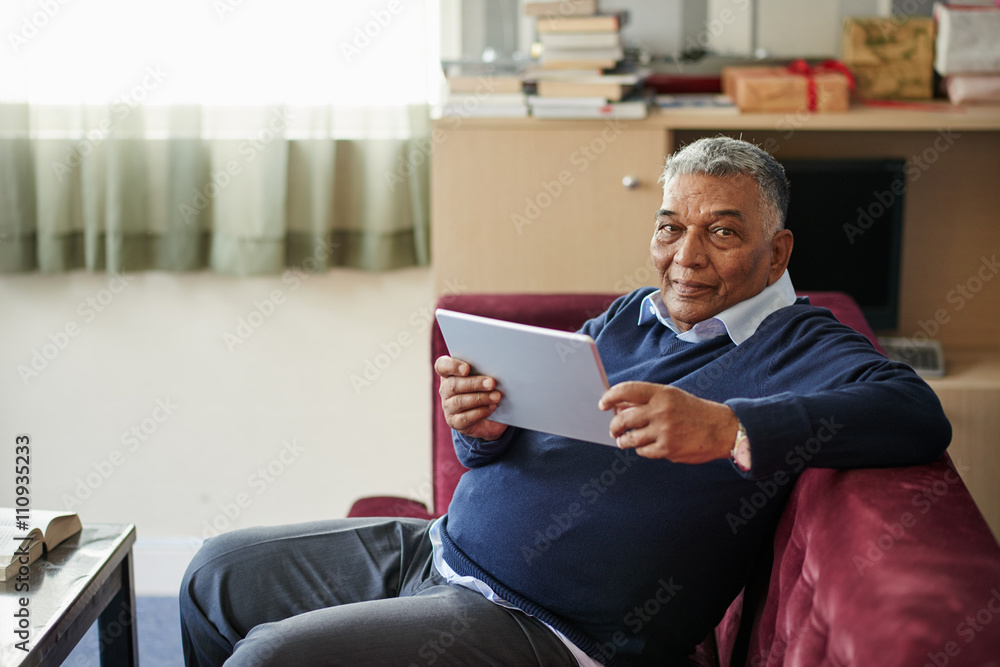 Mature man reading e-book when sitting on sofa Mature man reading e-book when sitting on sofa