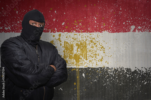 dangerous man in a mask standing near a wall with painted national flag of egypt
