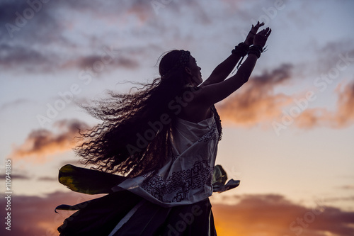 Silhouetted woman hula dancing wearing traditional costume at dusk, Maui, Hawaii, USA photo