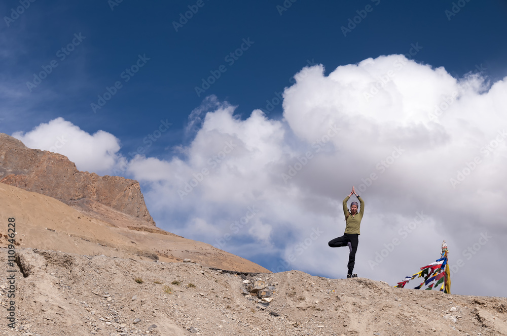 Obraz premium Young female practising yoga tree posture Vrksasana in mountains