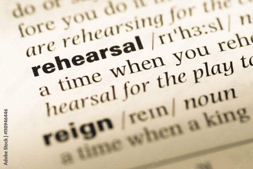 Close up of old English dictionary page with word rehearsal Close up of old English dictionary page with word rehearsal