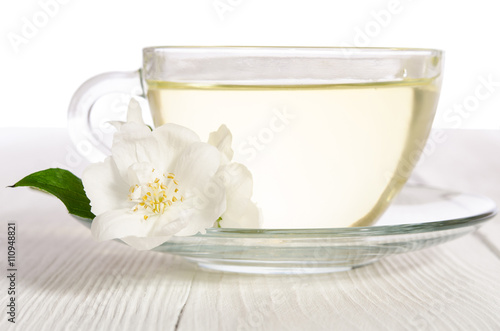 Glass cup of tea with jasmine on the white wooden table
