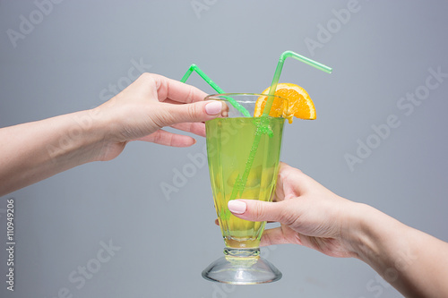 The female hands with cocktail on gray background