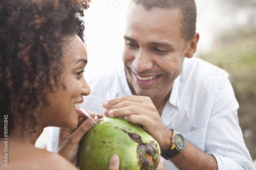 Close up of couple sharing coconut milk at beach, Rio De Janeiro, Brazil photo