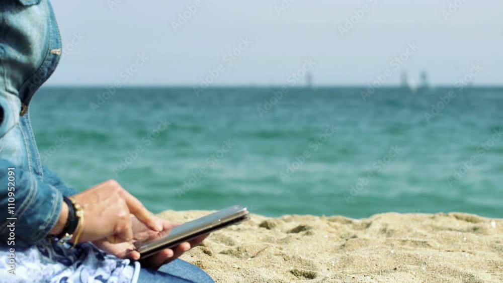 Woman sitting on the sand and using smartphone, steadycam shot
Woman sitting on the sand and using smartphone, steadycam shot