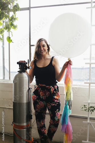 Portrait of young woman holding up helium balloon in design studio photo