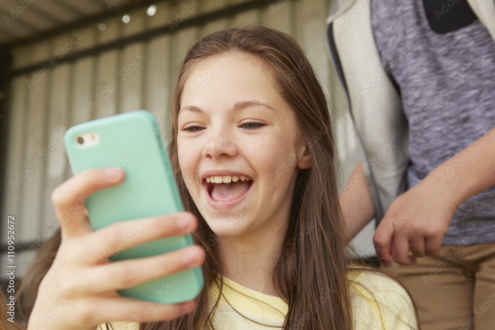 Girls laughing at smartphone in shelter Girls laughing at smartphone in shelter