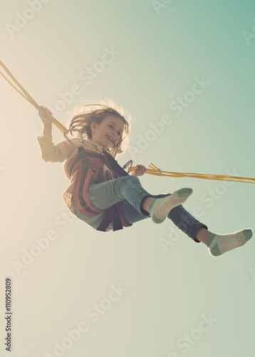 Canvas Print Little girl on bungee trampoline with cords. Place for text.