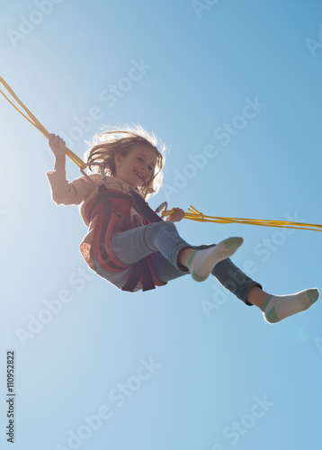 Billede på lærred Little girl on bungee trampoline with cords. Place for text.