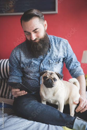 Young bearded man using smartphone on bed photo