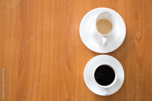 white cup of black coffee and milk jug on wood table