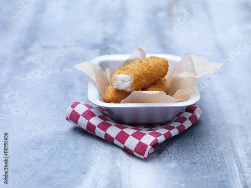 Fried chunky breaded cod fish fingers in baking tin on steel table