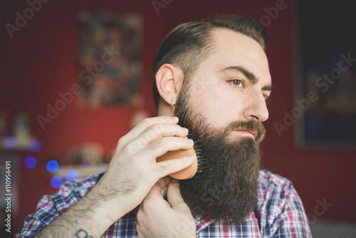 Young bearded man brushing his beard