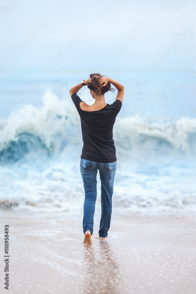 Alone beautiful woman standing in the sea during storm