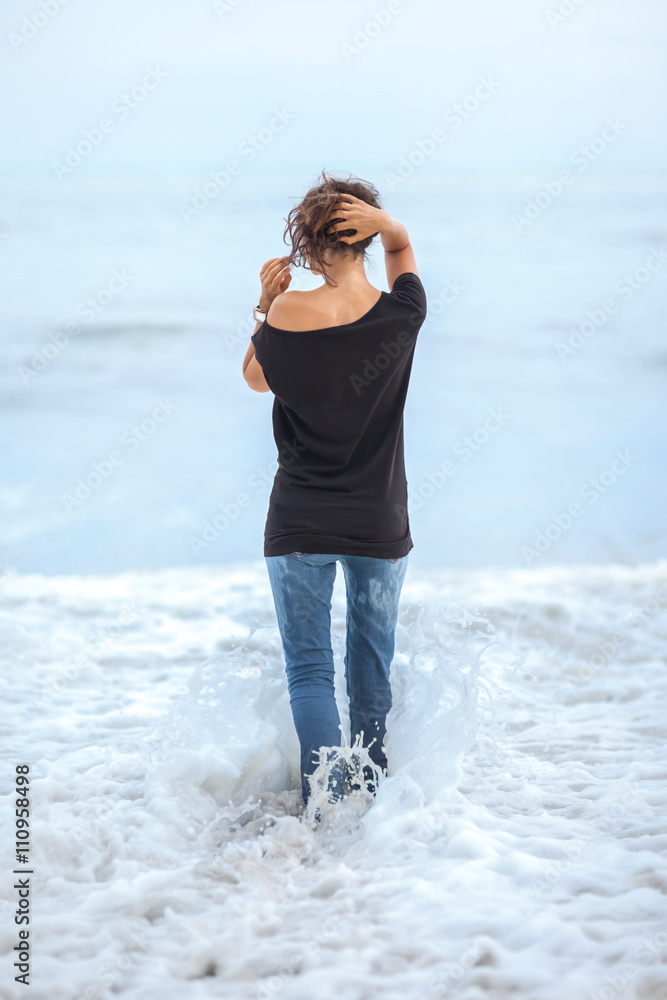 Alone beautiful woman standing in the sea during storm Alone beautiful woman standing in the sea during storm