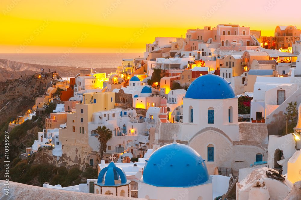 Picturesque view, Old Town of Oia or Ia on the island Santorini, white houses and church with blue domes at sunset, Greece