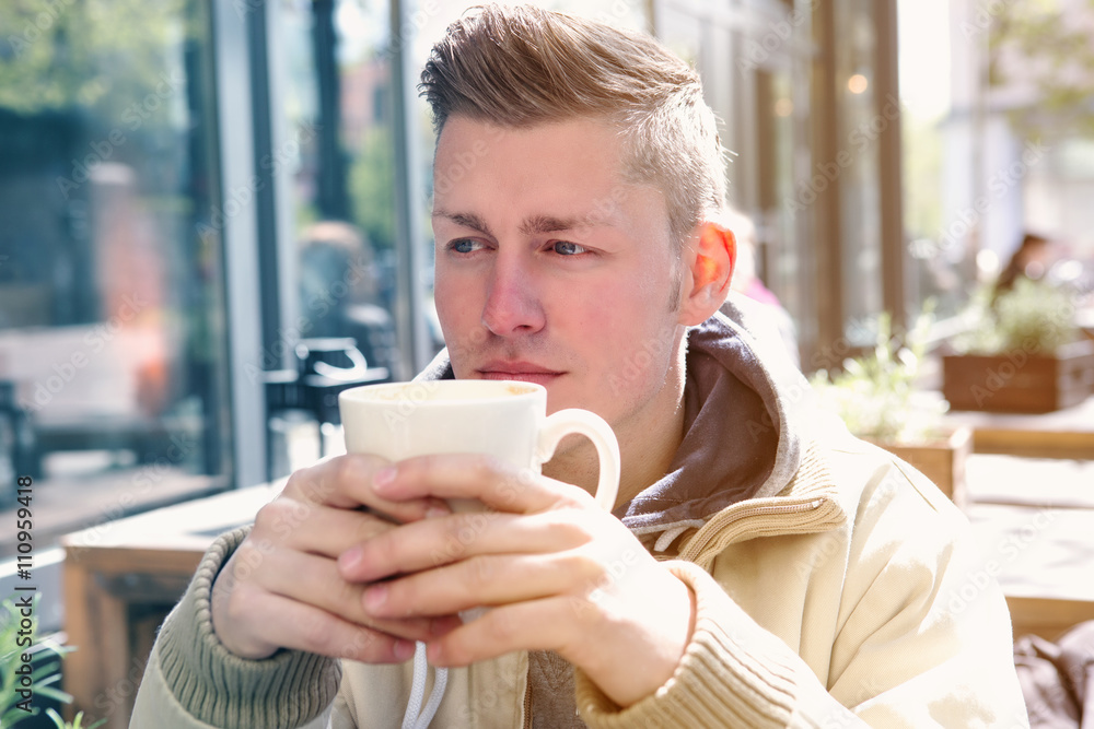 young man sitting outside and drinking coffee young man sitting outside and drinking coffee