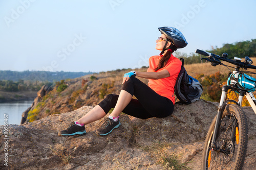 Adult attractive female cyclist is resting.