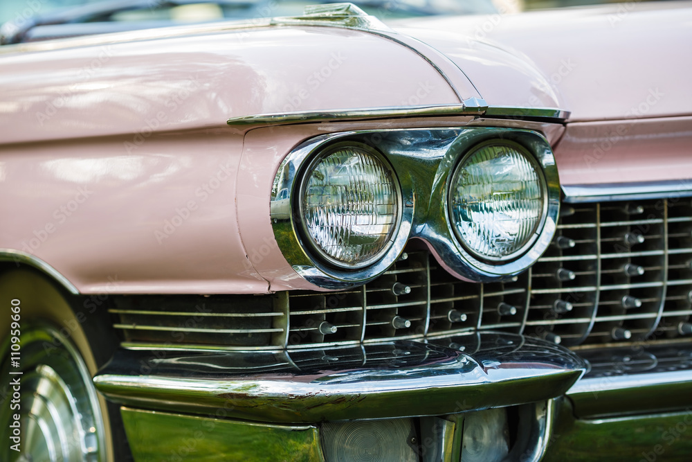 Detail on the headlight of pink vintage car. Selective focus.