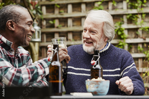 Senior men toast beer glasses in the garden photo