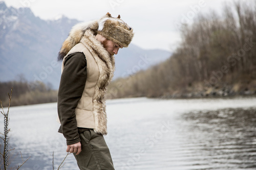 Mid adult man wearing trapper hat by river