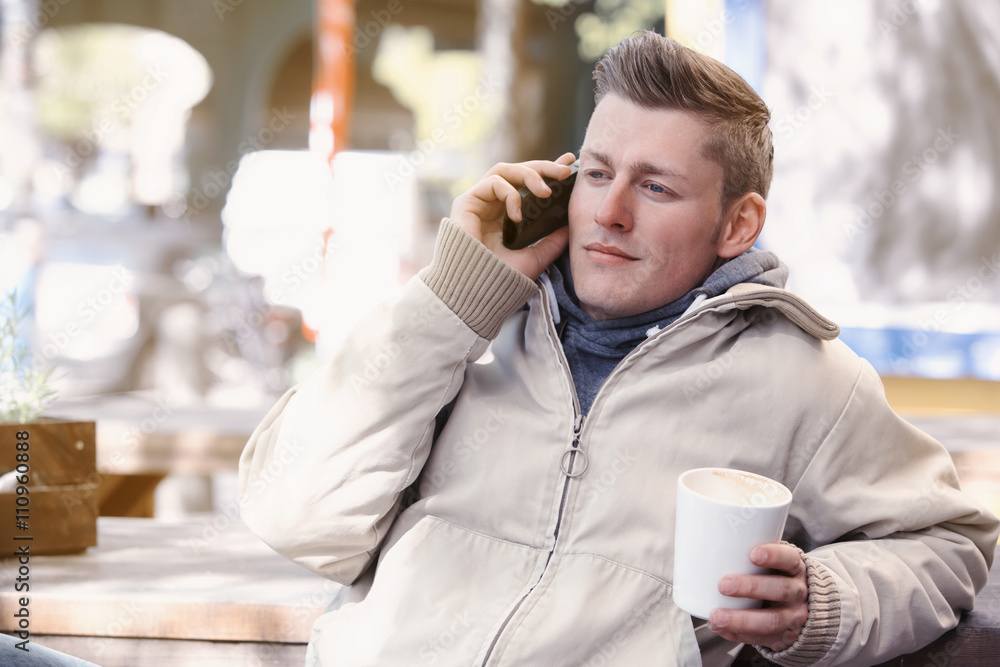 young man sitting outside and talking on the phone young man sitting outside and talking on the phone