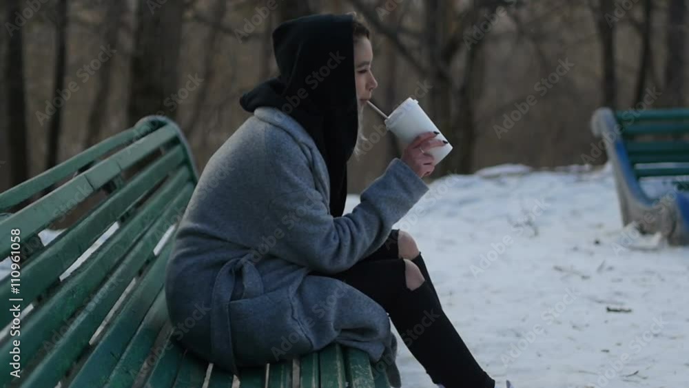 young girl drinking coffee in a winter park sitting on the bench young girl drinking coffee in a winter park sitting on the bench
