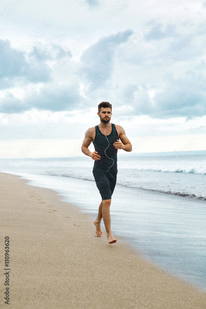 Sports. Handsome Fit Athletic Man Running On Beach. Sporty Runner Jogging Near Sea During Outdoor Workout. Healthy Active Jogger Exercising And Training For Marathon. Fitness Concept