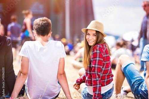 Teenage couple at summer music festival, sitting in front of sta photo