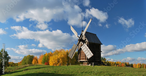 Old wooden windmill is in an autumn landscape