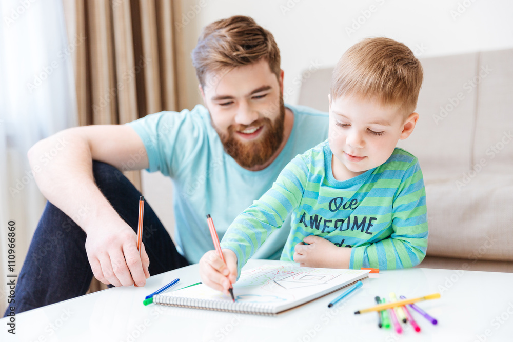 Happy little son and dad drawing with colorful markers Happy little son and dad drawing with colorful markers