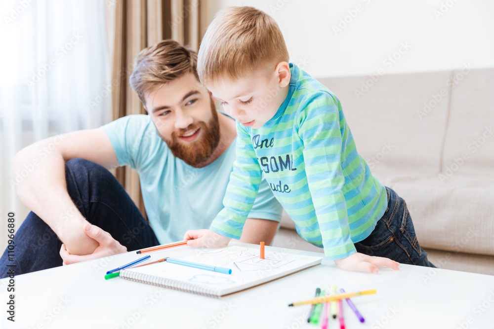 Happy little boy and his father drawing together Happy little boy and his father drawing together