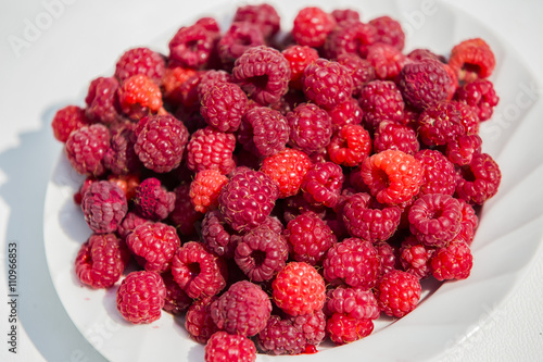 lots of ripe red raspberries on a plate