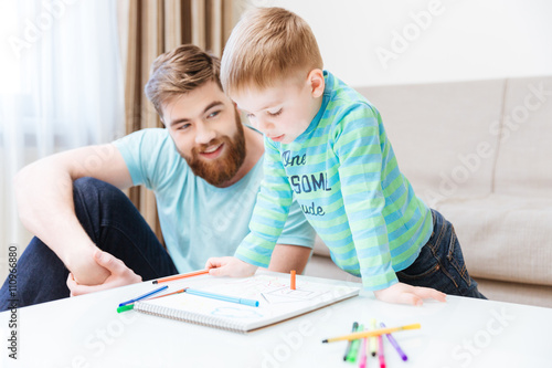 Happy little boy and his father drawing together