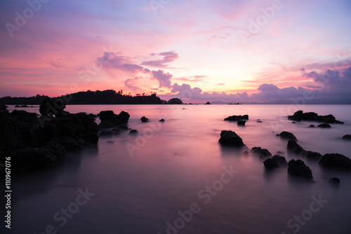 long exposure seascape with rock and sunset.