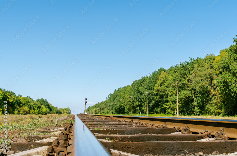 old railway closeup and trees along it under deep blue sky