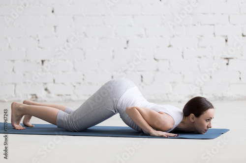 Attractive young woman doing Eight-Limbed yoga Pose in white lof