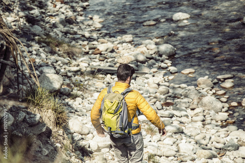 Rear view of young male hiker moving down to Toce river, Vogogna, Verbania, Piemonte, Italy