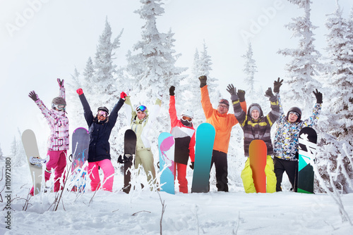 Obraz na plátně Group of friends skiers and snowboarders having fun on snowbound winter forest
