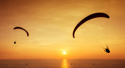 Fotobehang Luchtsport Skydivers silhouetten boven zee zonsondergang  © cppzone